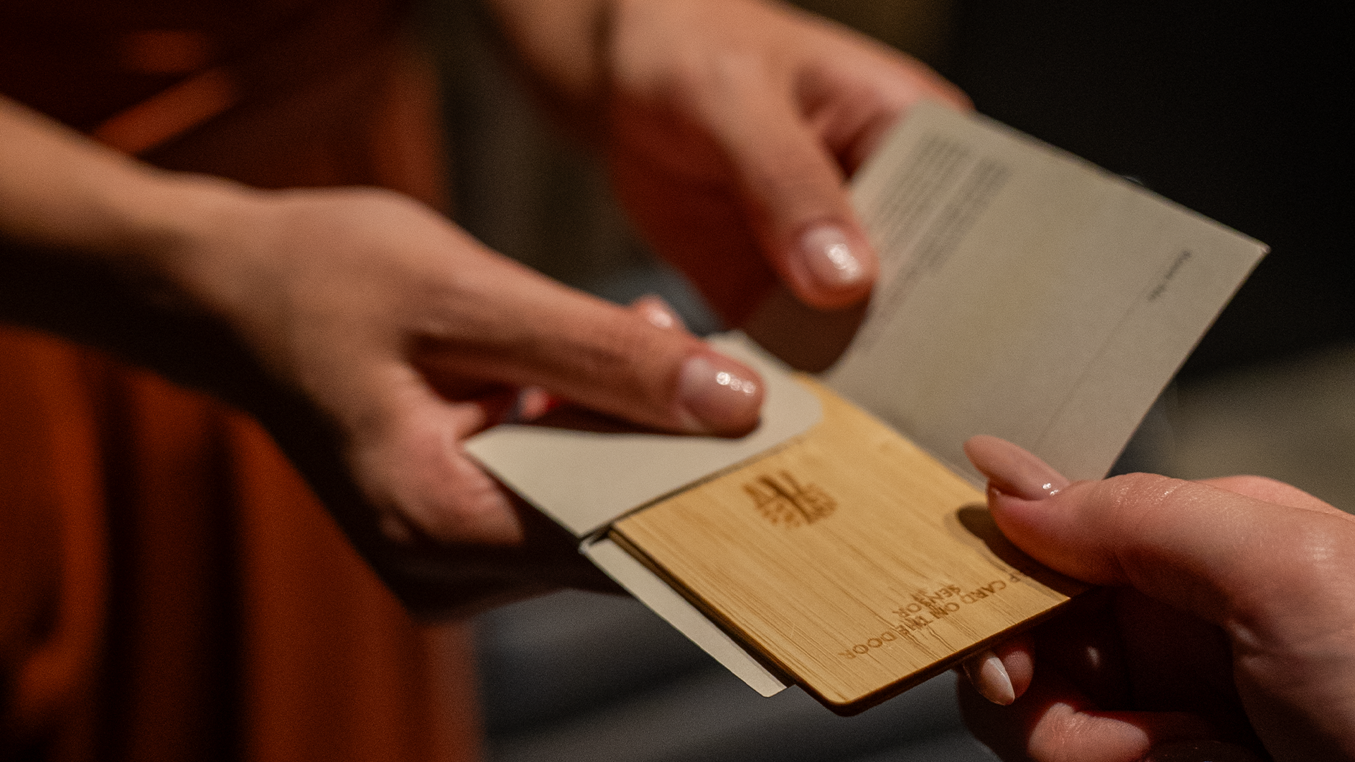 Hands exchanging a bamboo cardholder at Banyan Tree Dubai, focusing on sustainable luxury.